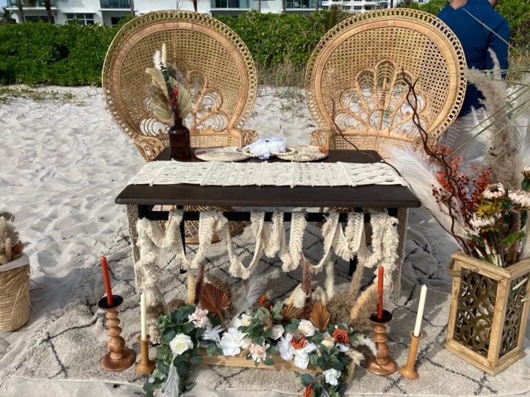 Beach sweetheart table with two peacock chairs and boho pampas decor