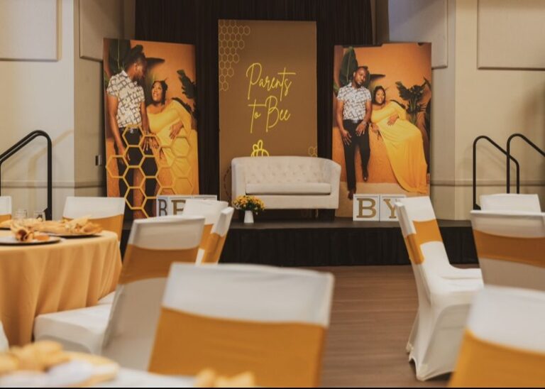 Parents to Bee baby shower with an ivory loveseat and gold chair sashes