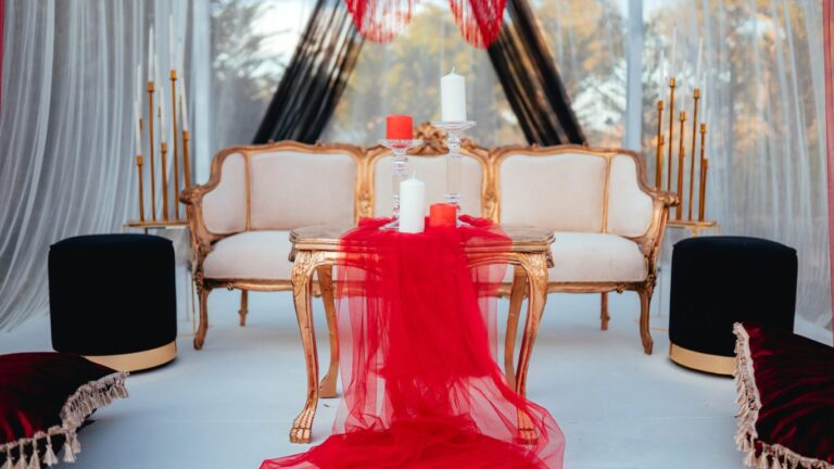 Gold frame loveseats with a red table runner and candles