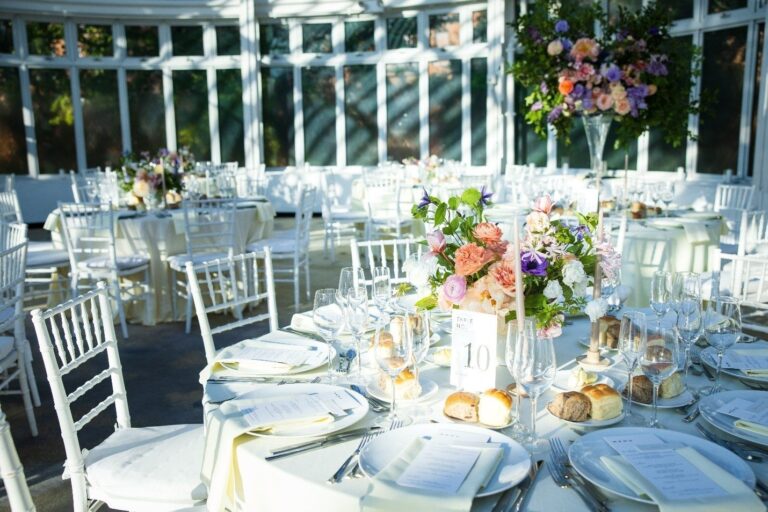 Engagement party tables with colorful florals in a glass conservatory