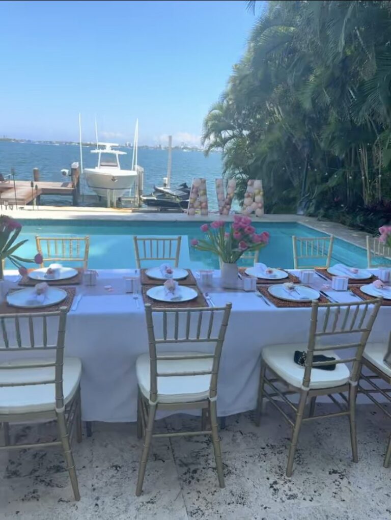 Poolside dinner table with gold chiavari chairs overlooking the water