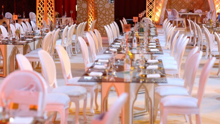 Wedding reception with long tables, white chairs and warm lighting